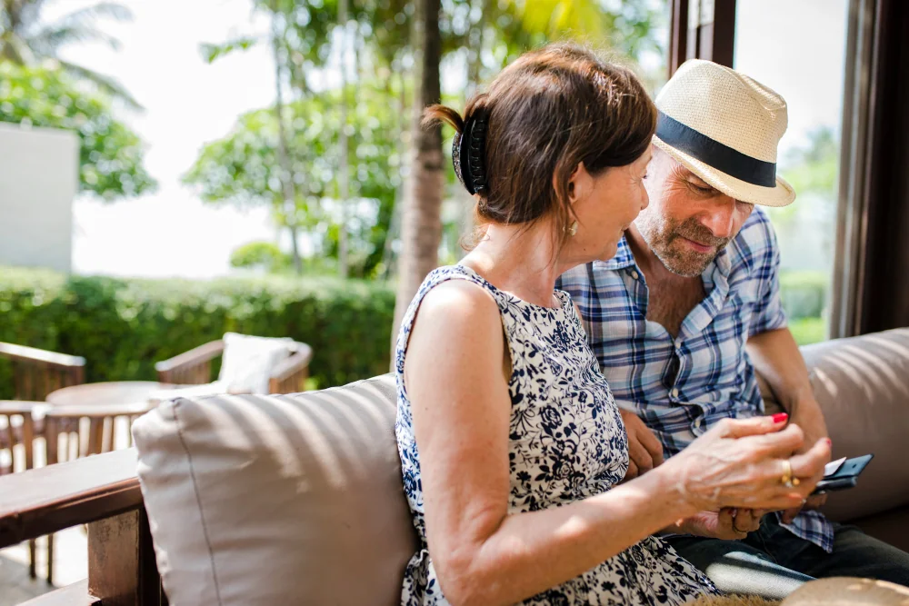 A mature couple looking at a phone while sitting outdoors