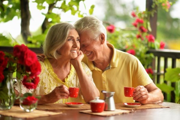 Two adults talking over coffee at an outdoor table