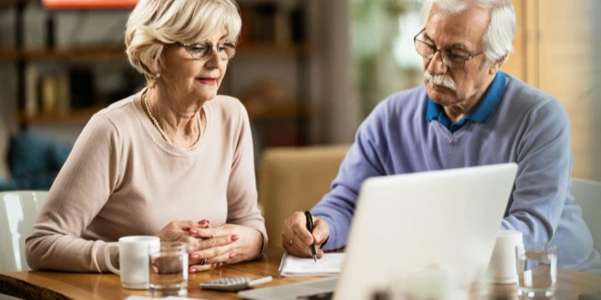 Two older adults reviewing a dating website together on a laptop